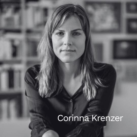 Schwarz-weiß Porträt der Autorin Corinna Krenzer. Sie blickt ruhig in die Kamera, im Hintergrund ist ein unscharf angedeutetes Bücherregal zu sehen.