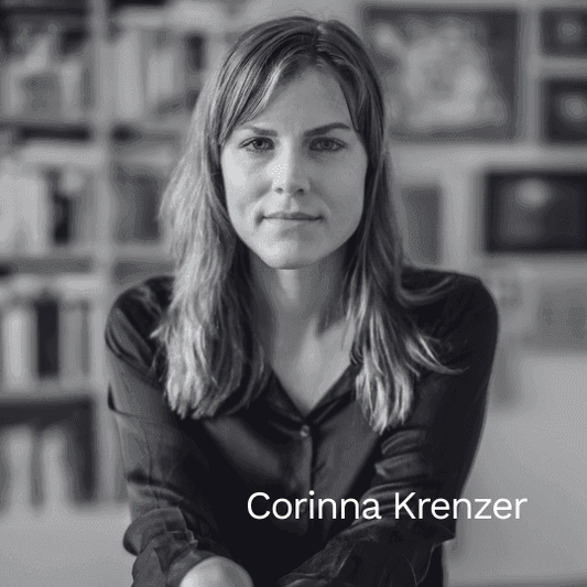 Schwarz-weiß Porträt der Autorin Corinna Krenzer. Sie blickt ruhig in die Kamera, im Hintergrund ist ein unscharf angedeutetes Bücherregal zu sehen.