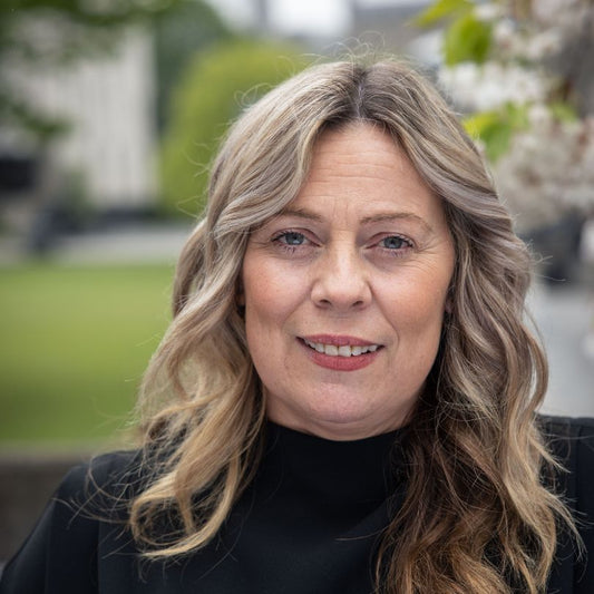 Porträt von Katriona O’Sullivan, Autorin von 'Working Class Girl', Psychologin und Aktivistin, vor grünem Hintergrund im Freien.