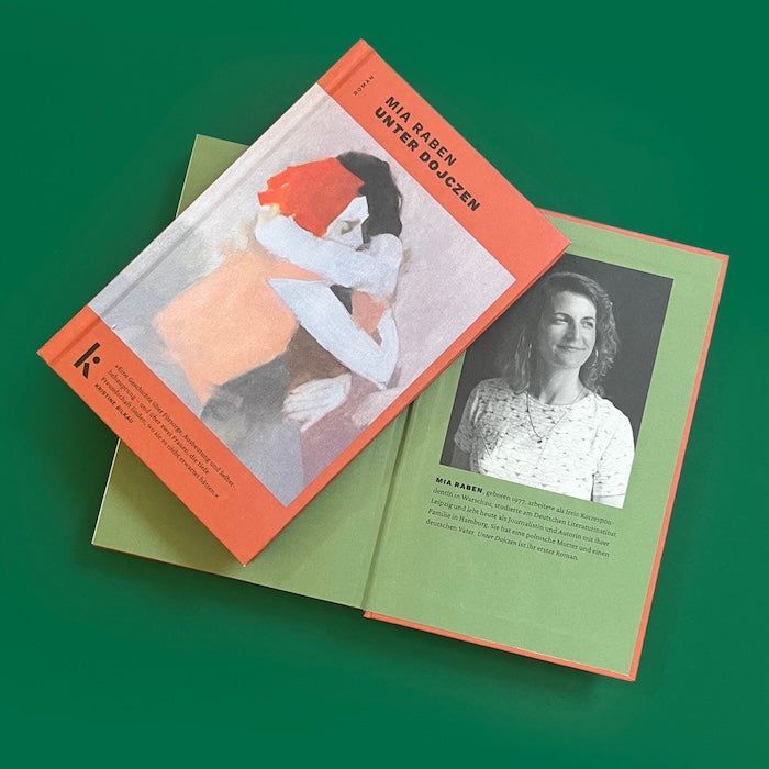Foto von »Unter Dojczen«, aufgeschlagen mit Autorinnenfoto von Mia Raben im Hintergrund, Cover im Vordergrund.