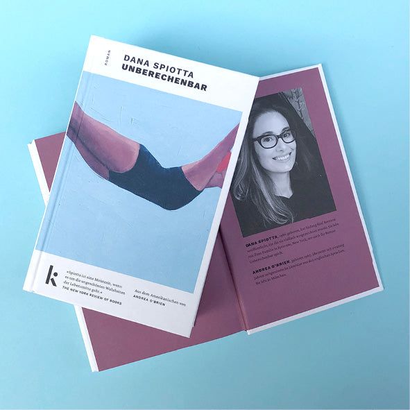 Foto von »Unberechenbar«, aufgeschlagen mit Autorinnenfoto im Hintergrund, Cover im Vordergrund.