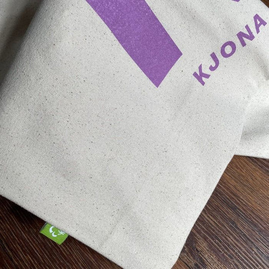 Detailansicht der Kjona Bio-Baumwolltasche mit lila K-Logo und GOTS-Label, robuste Qualität mit 340 g/m² Stoffdichte.