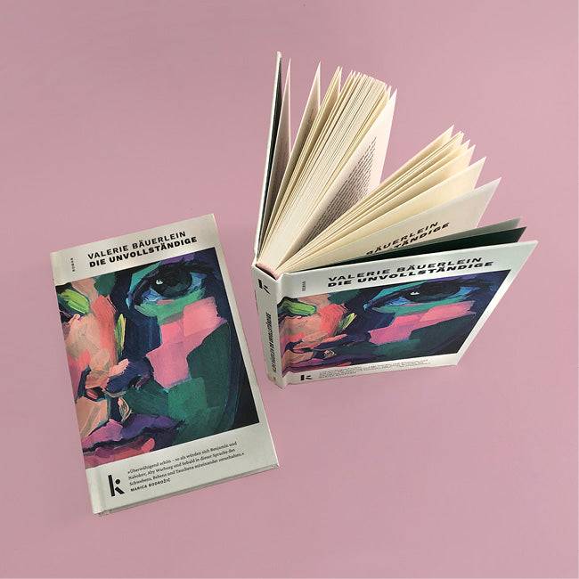 Foto von »Die Unvollständige«, links Cover vom Buch, rechts daneben aufgestelltes Buch von oben. 