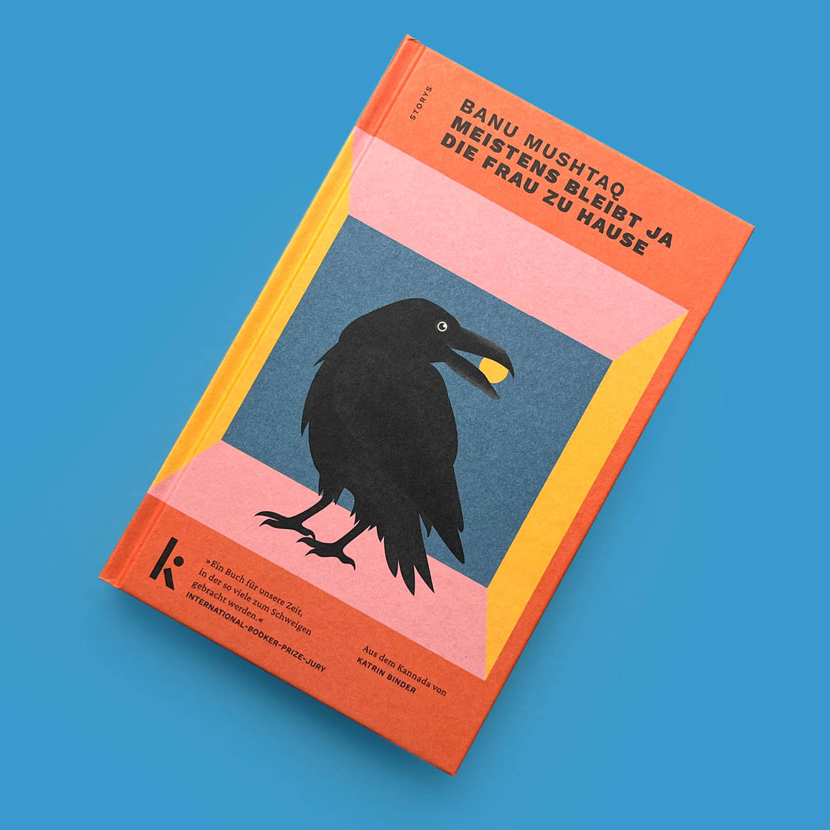 Frontansicht des Buchs „Meistens bleibt ja die Frau zu Hause“ von Banu Mushtaq vor blauem Hintergrund. Das Cover zeigt eine Rabe-Illustration auf orange-rosa Grund.