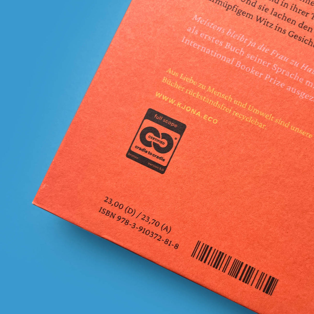 Nahaufnahme der Rückseite des Buchs von Banu Mushtaq mit Klappentext-Ausschnitt, Cradle to Cradle-Siegel und ISBN-Barcode auf orangefarbenem Grund.