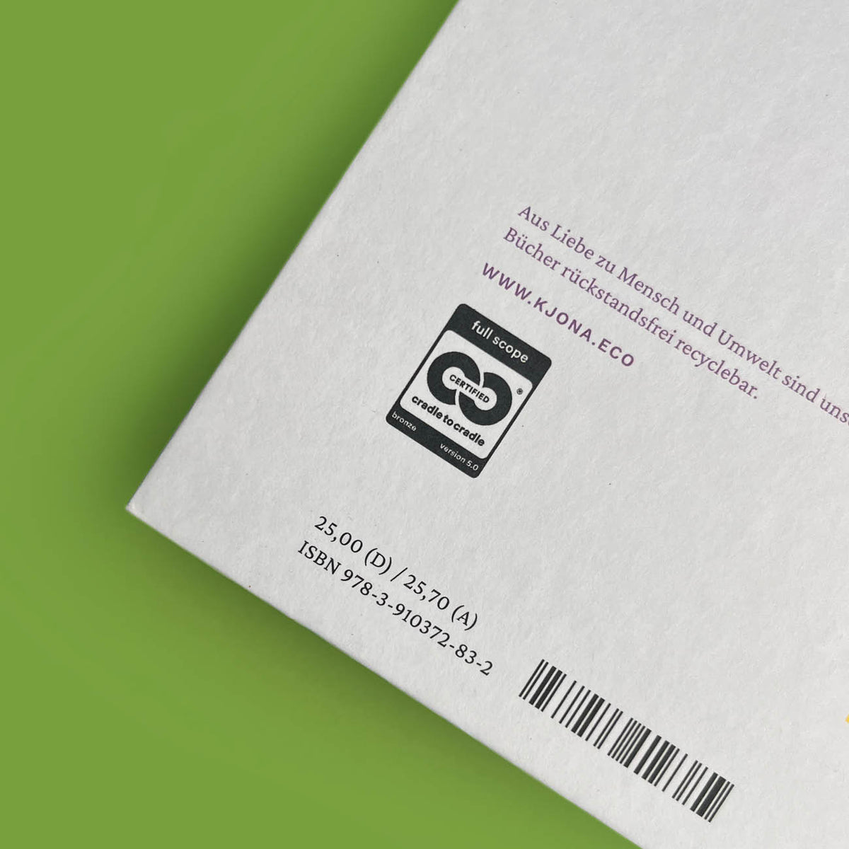 Nahaufnahme der Rückseite mit dem Cradle to Cradle Certified Bronze-Siegel, der Kjona-Webadresse, Preisangaben und Barcode.