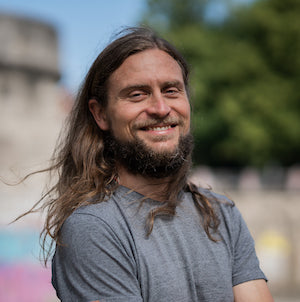 Wenn du hier nicht das Porträt von Flo siehst, dann läuft etwa schief. Der ebenfalls "junge" Mann sollte ansonsten mit seiner schicken Matte vor einem verschwommenen Wald stehen. Haben wir irgendwann 2021 an der Isar fotografiert. Wir heißt in dem Fall Nina Rühr von SINN MEDIA. 🥳