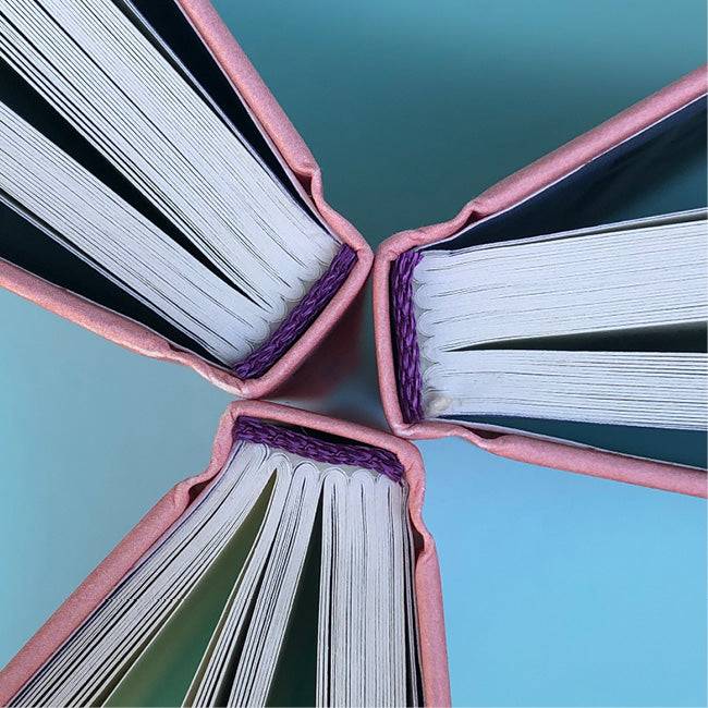 Ausschnitte der Buchseiten von »Kleine Kratzer«, drei Bücher Rücken an Rücken, von oben. 