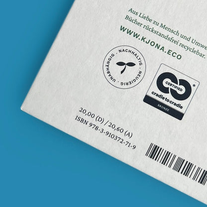 Nahaufnahme der unteren Buchrückseite auf blauem Grund. Zu sehen sind der Webseiten-Link www.kjona.eco, ein rundes Siegel mit der Aufschrift „Unabhängig. Nachhaltig. Neugierig.“, das „Cradle to Cradle Certified Bronze“-Logo, die Preisangabe sowie der Barcode mit der ISBN-Nummer.